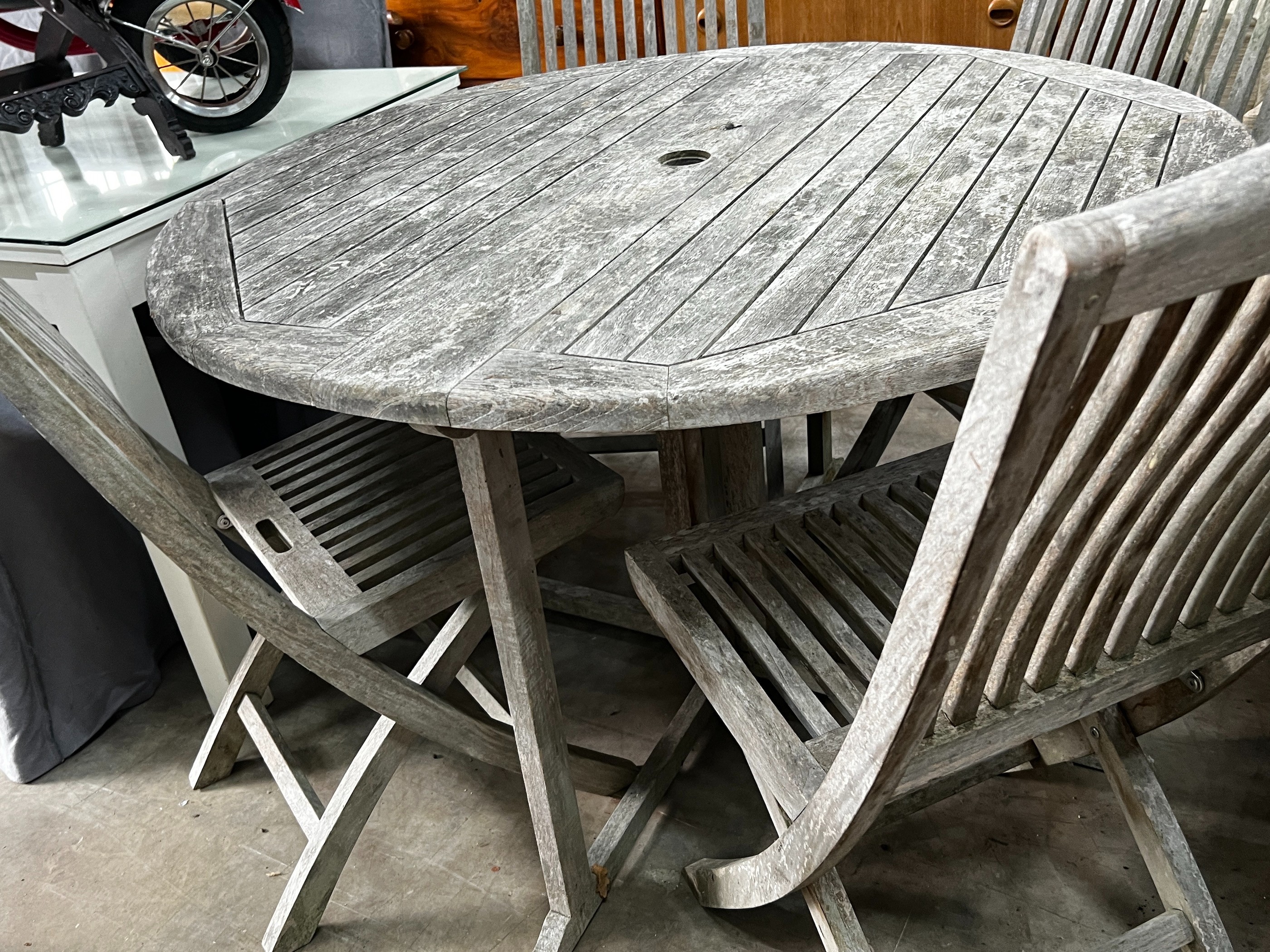 A Jo Alexander circular weathered teak folding garden table, diameter 120cm, height 75cm and four chairs *Please note the sale commences at 9am.